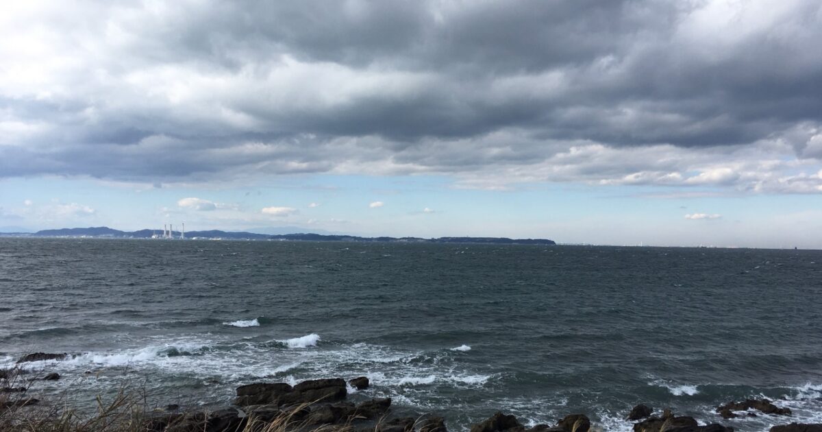 曇り空と波立つ海岸線の風景