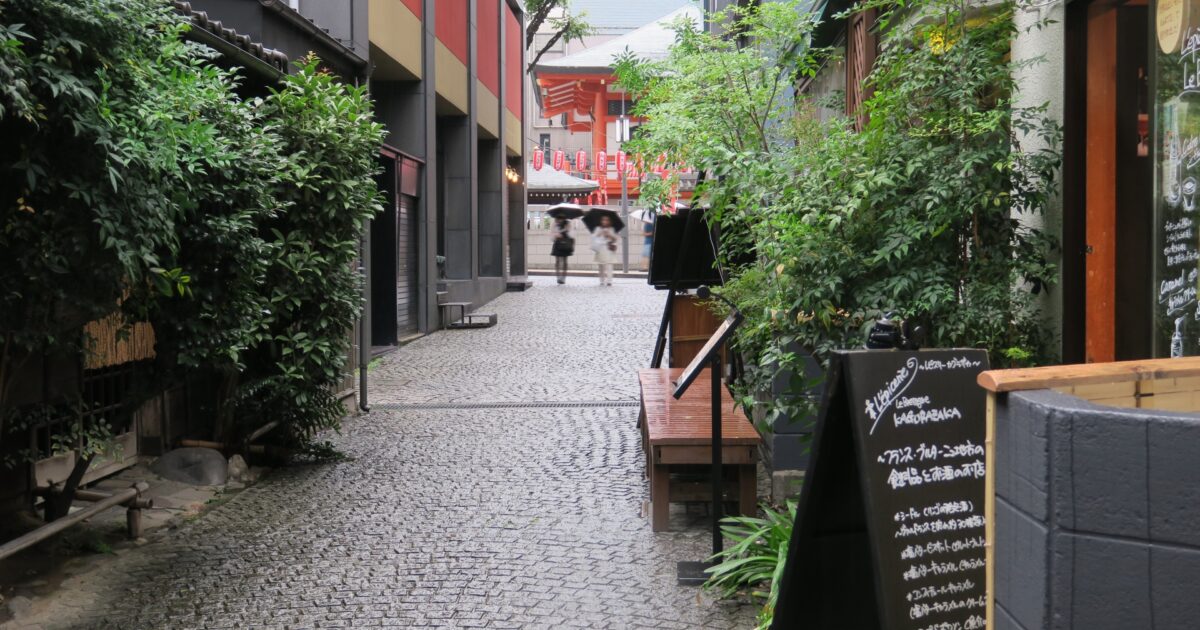 石畳の路地と傘を差して歩く人々の後ろ姿