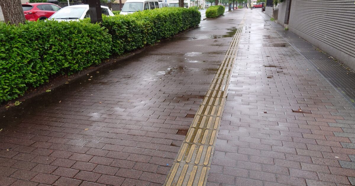 雨で濡れた点字ブロックのある歩道