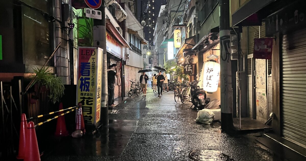 雨に濡れた夜の路地裏と灯りが灯る飲食店