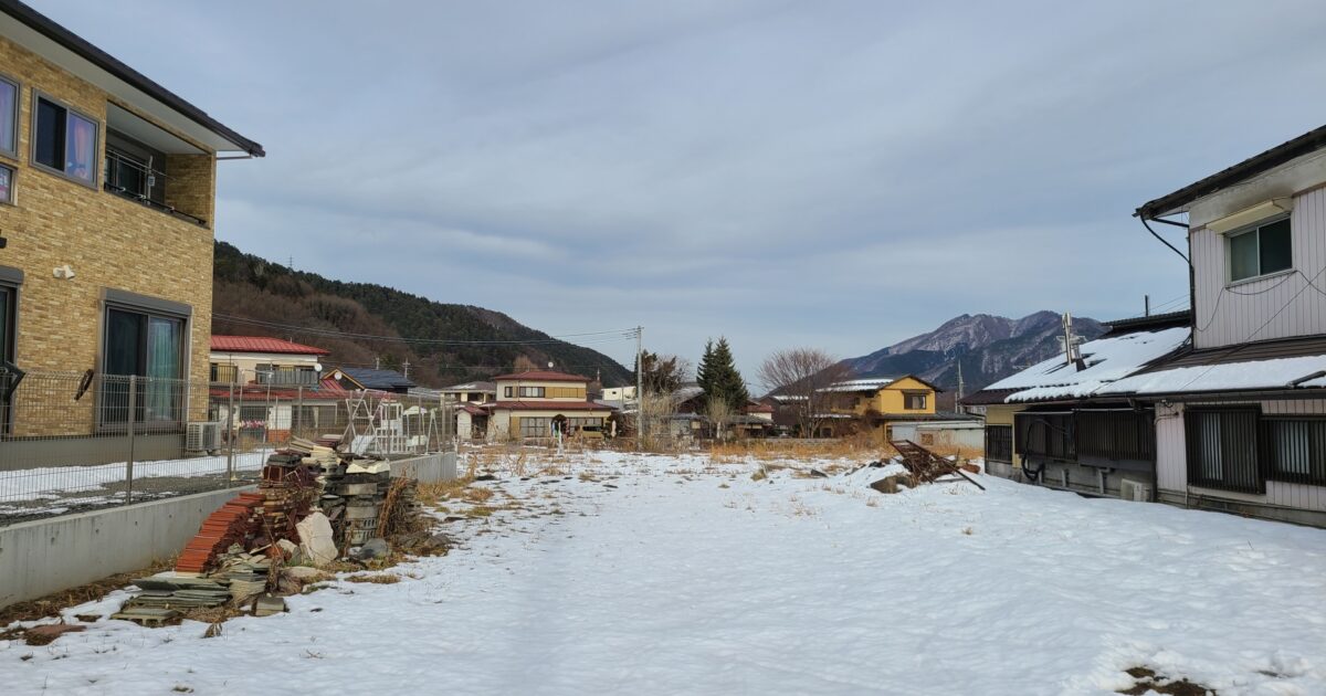 雪が残る地方の住宅地と山の風景