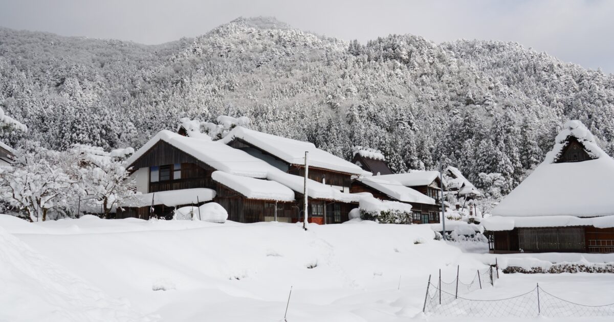 雪に覆われた合掌造りの古民家と山の風景