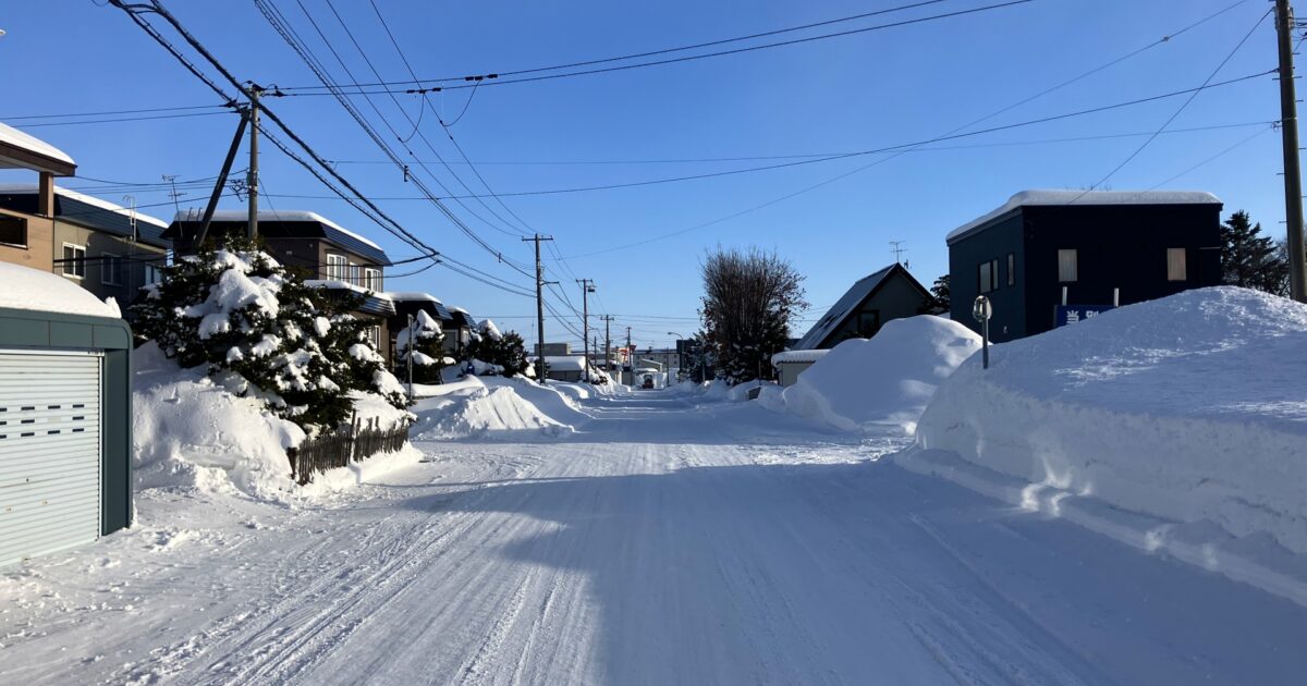 晴天の下の住宅街と積雪した道路の風景