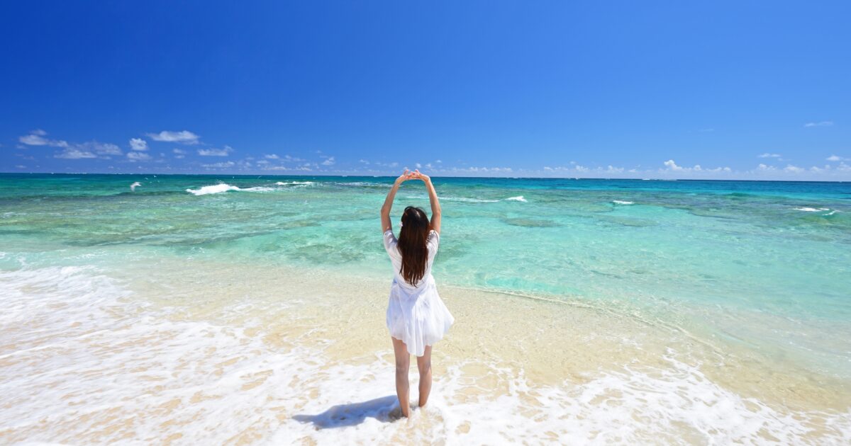 青い海を見つめる女性の後ろ姿