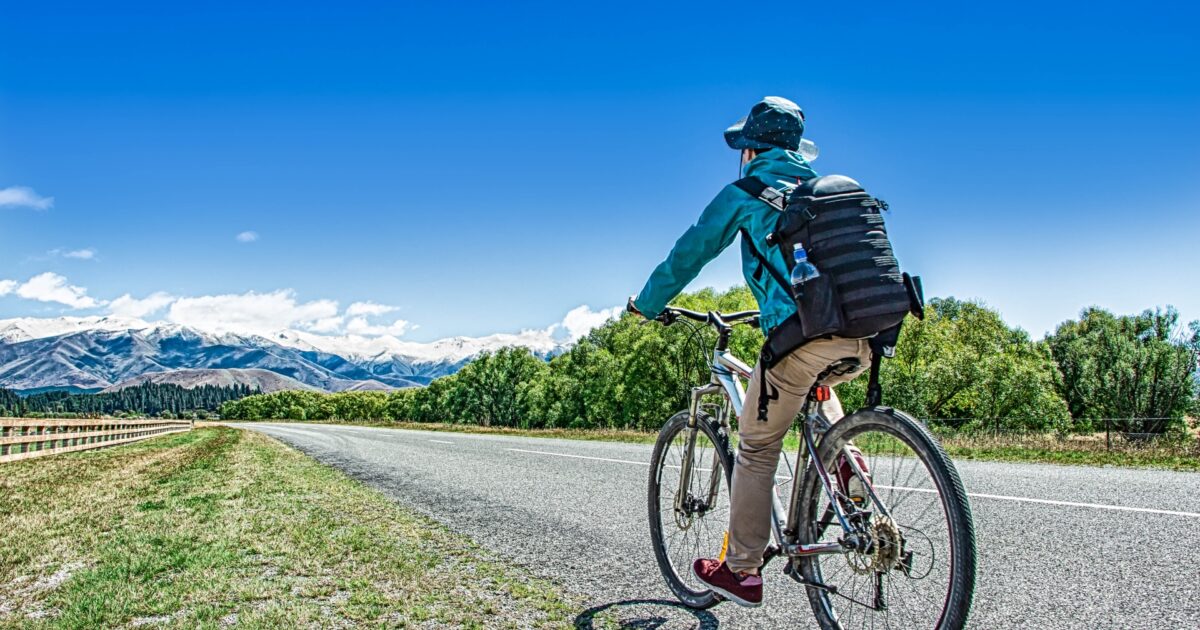 青空の下で自転車に乗る男性と山の風景