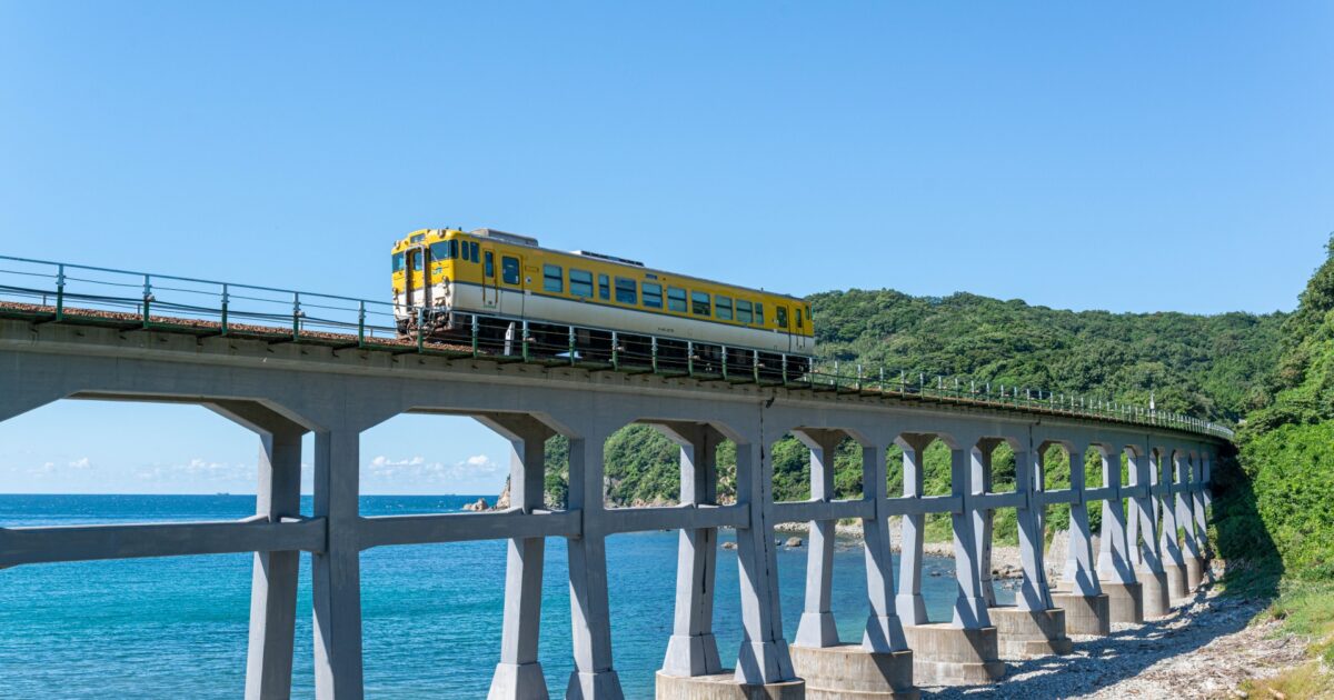 海沿いの高架橋を走る黄色い列車