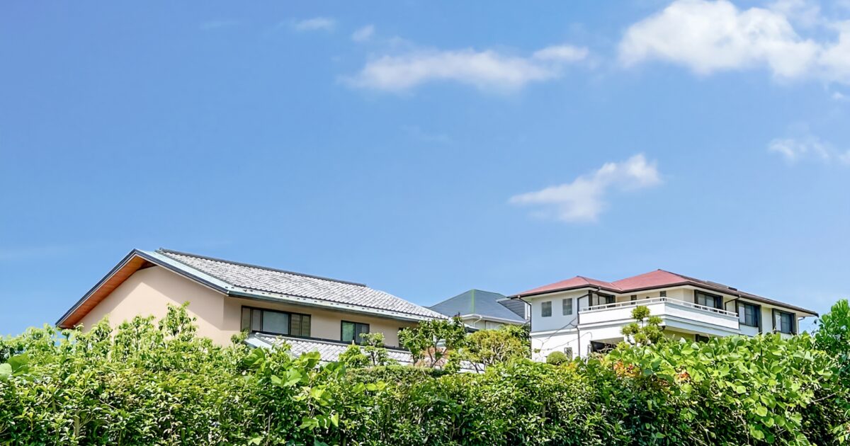 青空の下に並ぶ住宅と生け垣