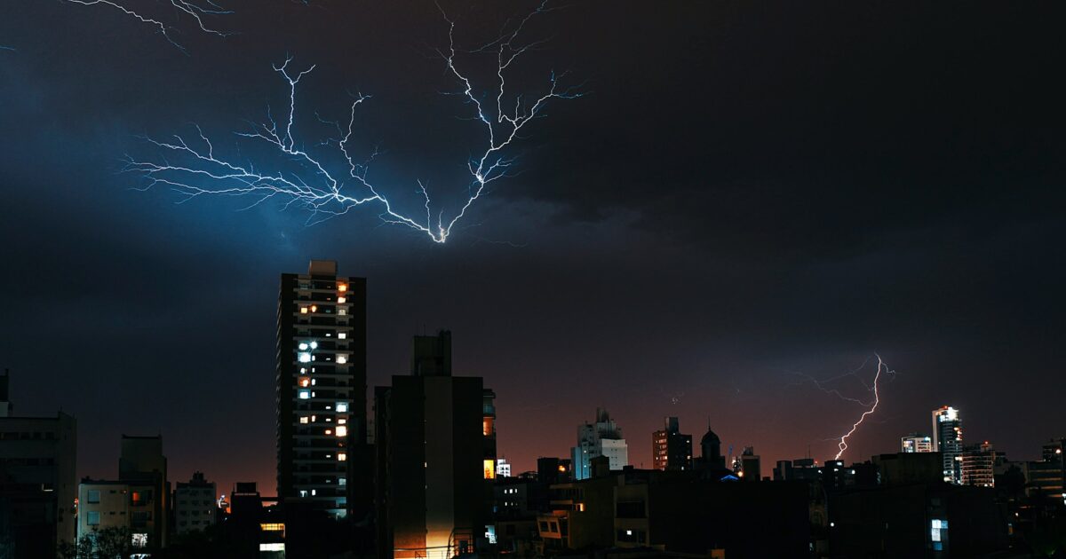 夜空を走る稲妻と高層ビル群の都市風景