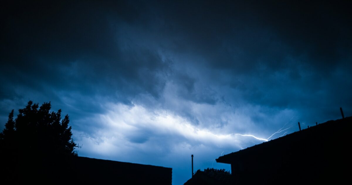住宅街の夜空に光る雷と暗い雲
