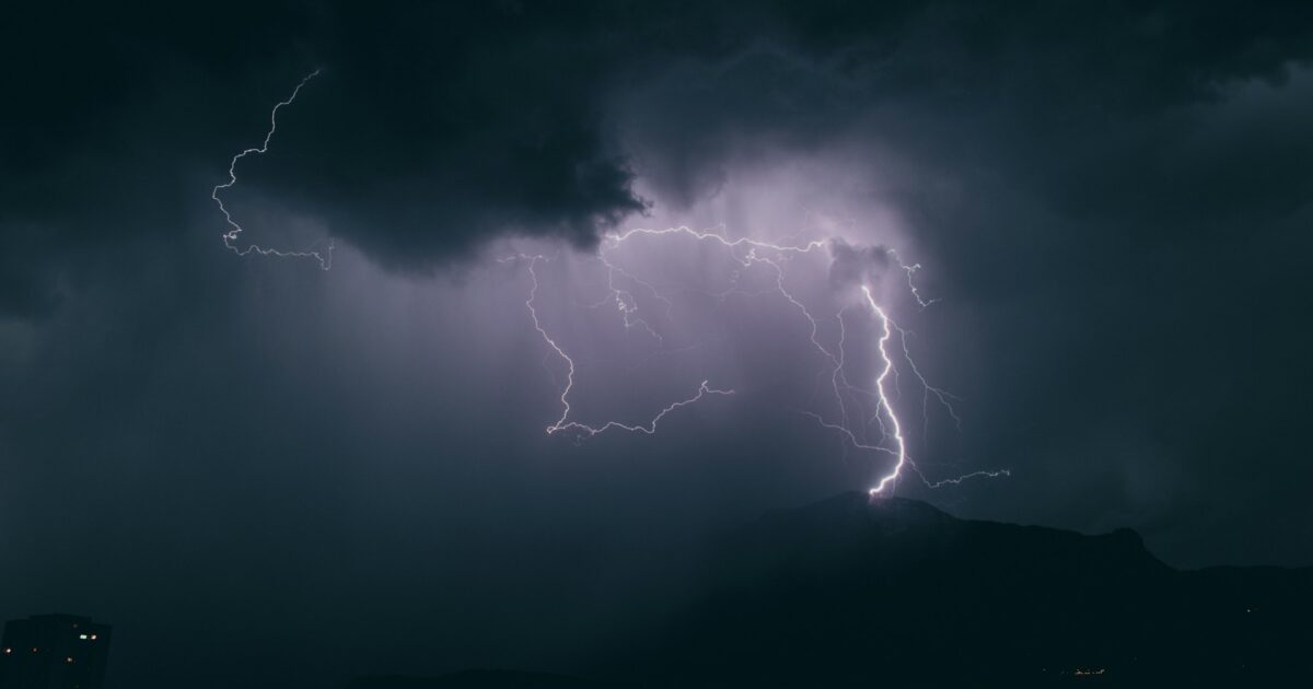 山に落ちる稲妻と雷雲の暗い夜空