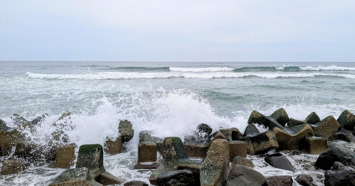 防波堤に打ち寄せる波しぶきと荒れた海
