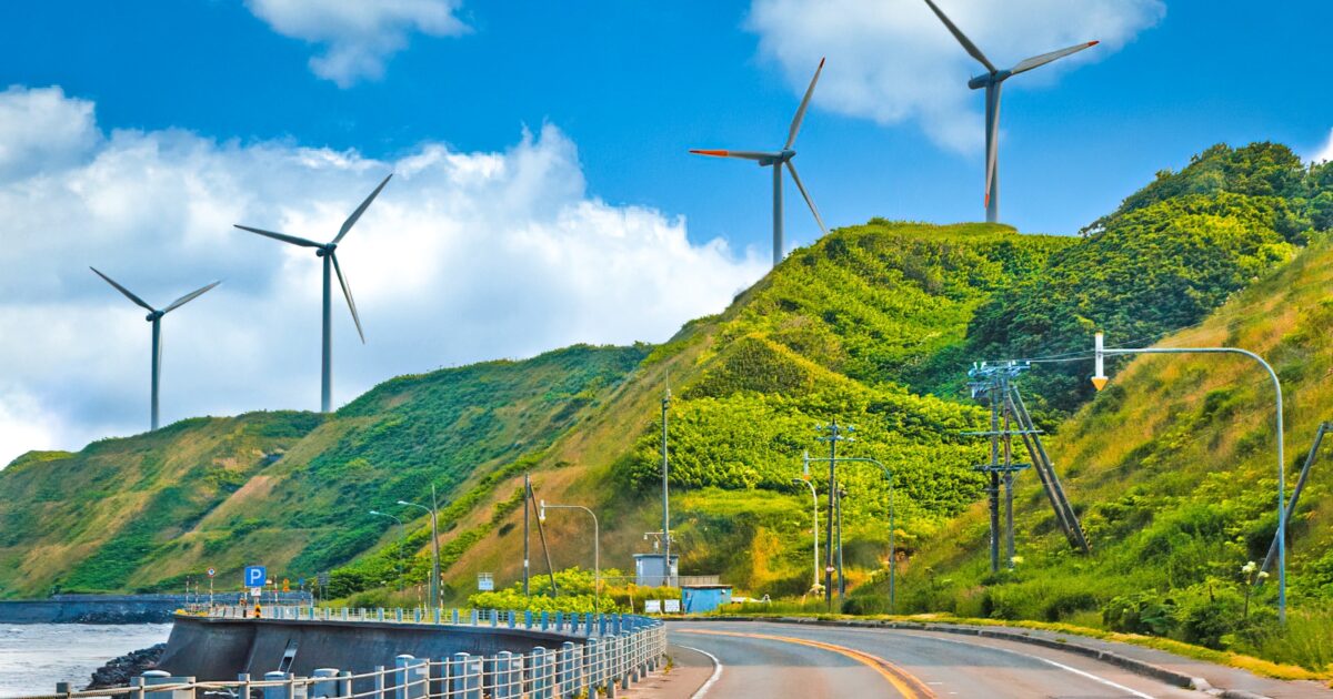 青空と風車が並ぶ海沿いの道路風景